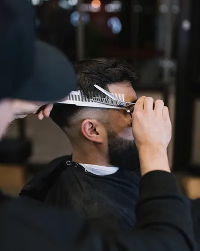 Hombre cortando el pelo a otro con tijeras